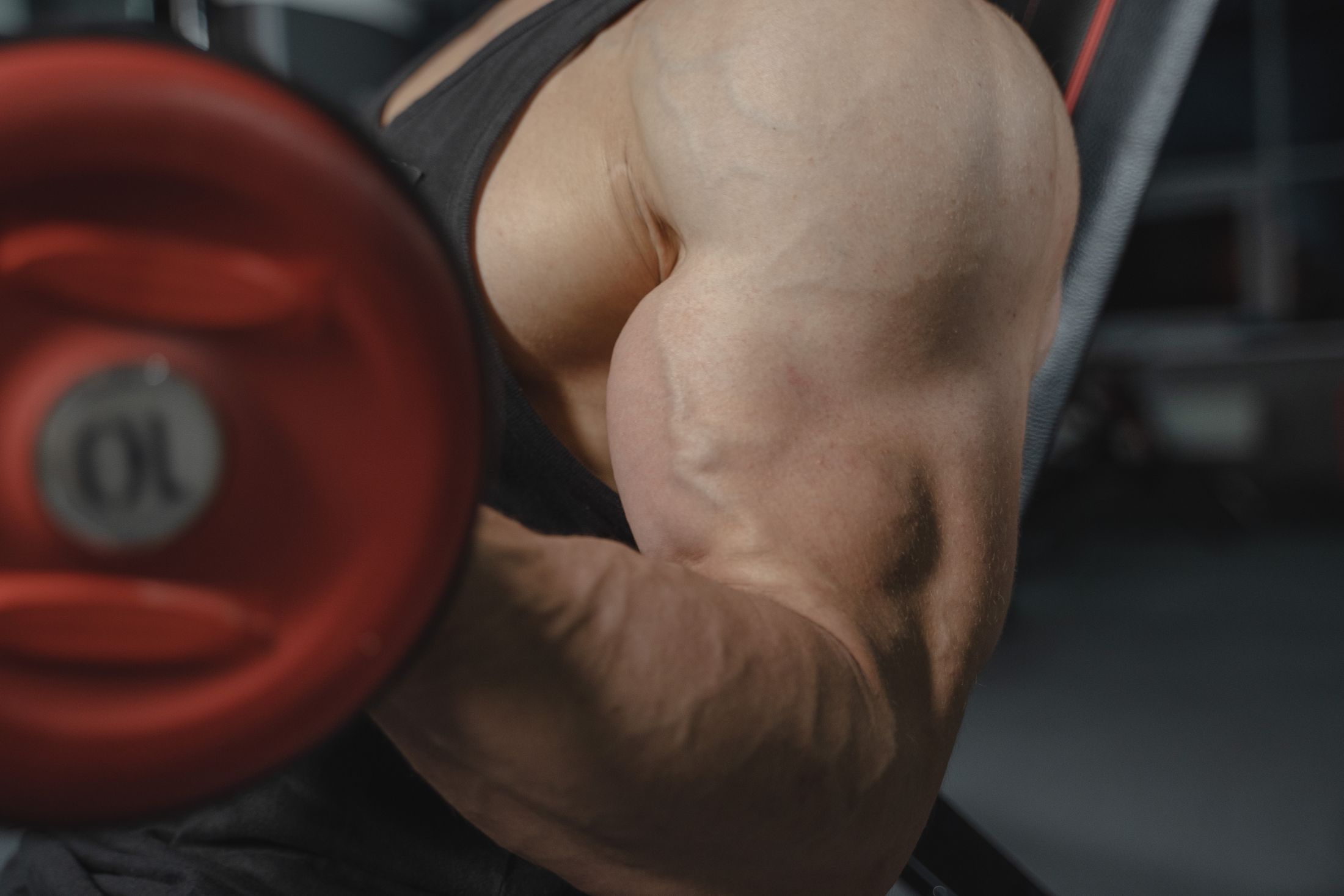 Nahaufnahme eines angespannten Oberarms beim Heben einer Kurzhantel im Fitnessstudio