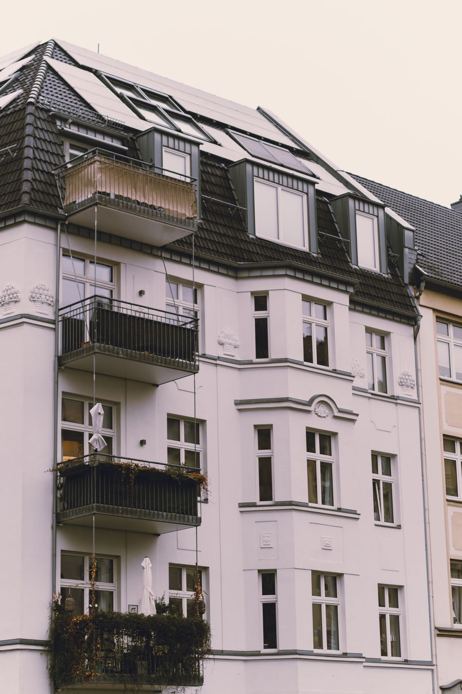 Europäisches Mehrfamilienhaus mit Balkonen und Solarpanelen an der Fassade