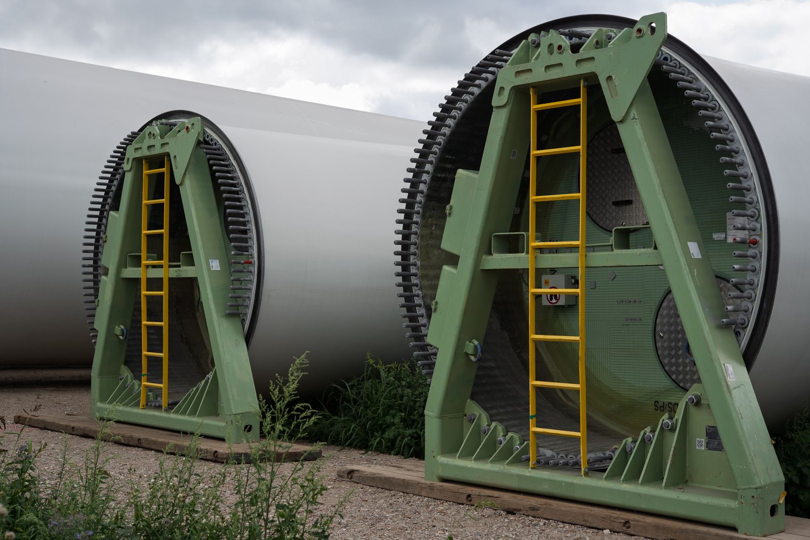 Zwei Rotorblätter einer Windkraftanlage aus Faserverbundwerkstoff liegen in grünen Transportgestellen