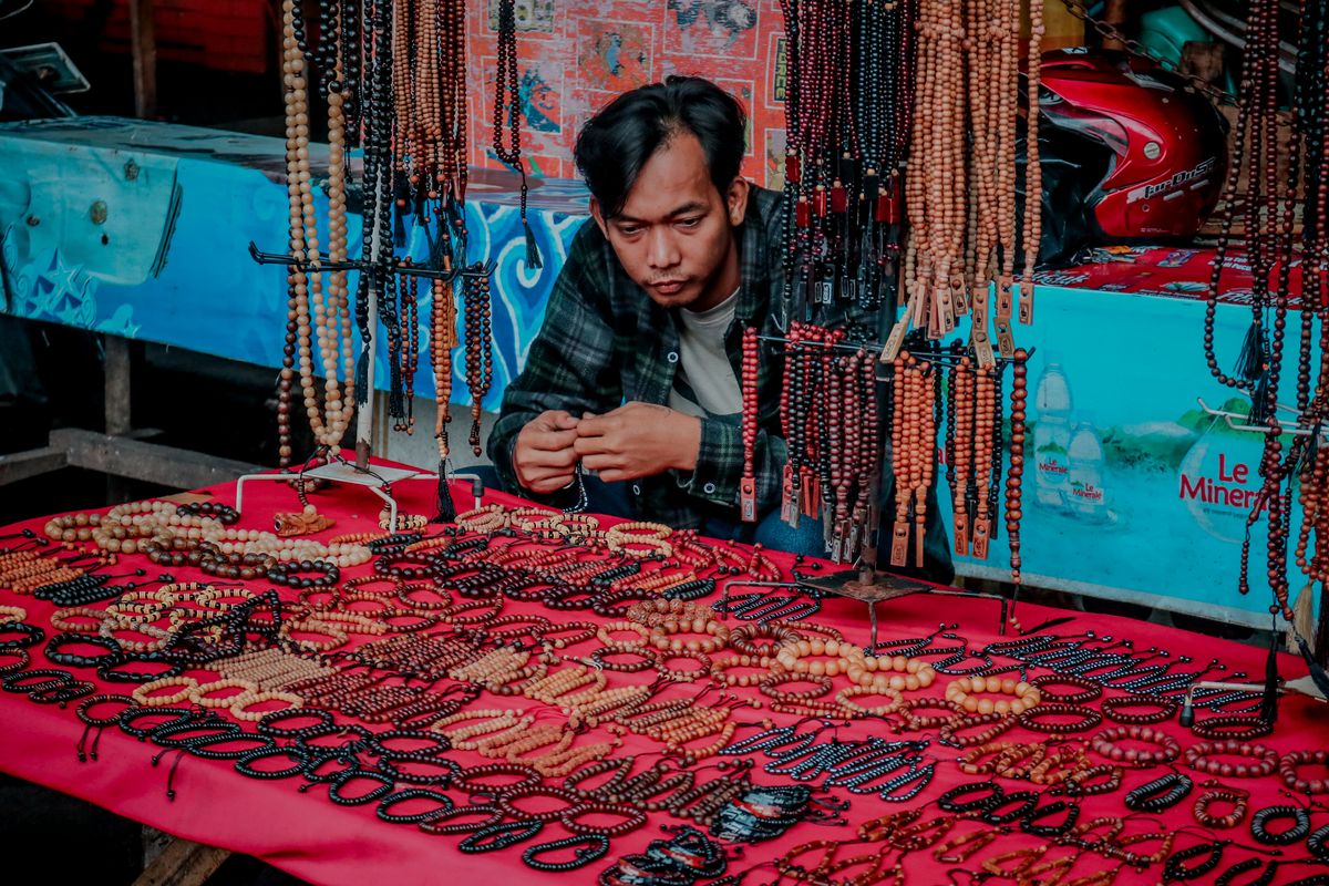 Verkäufer an einem Stand mit handgemachten Holzperlen-Armbändern und Ketten