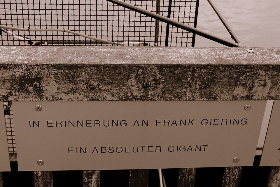 Gedenktafel an einem Brückengeländer mit der Inschrift In Erinnerung an Frank Giering, ein absoluter Gigant