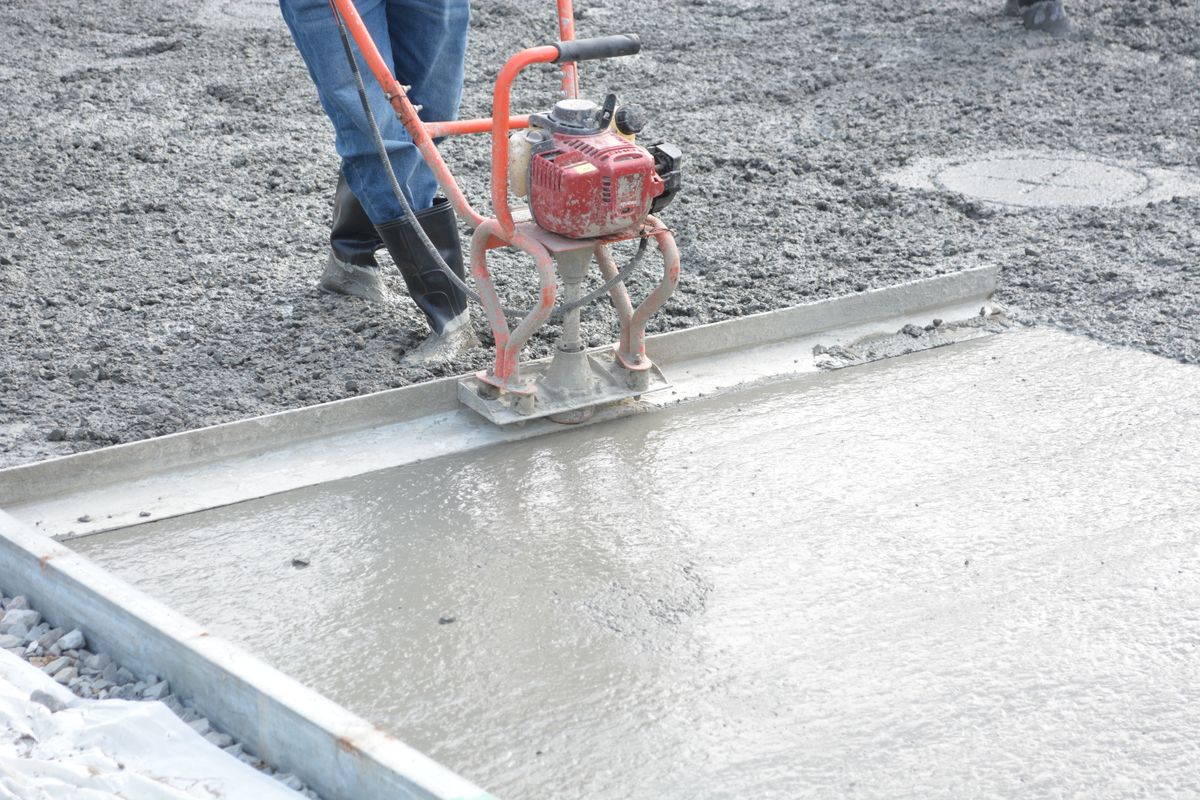 Bauarbeiter glättet frisch gegossenen Estrichboden auf einer Baustelle