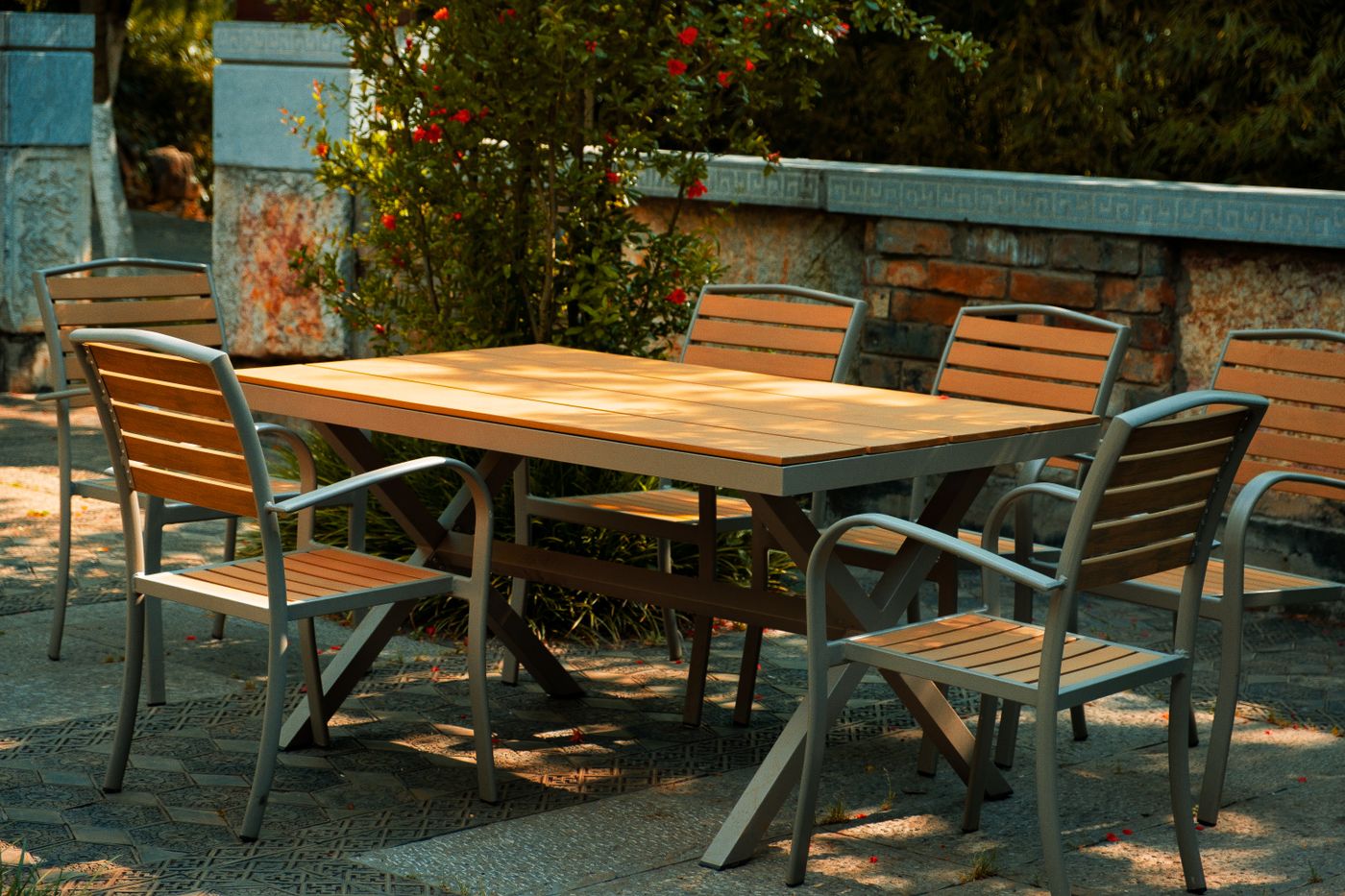 Gartentisch mit Holzplatte und sechs Armlehnstühlen auf einer schattigen Terrasse