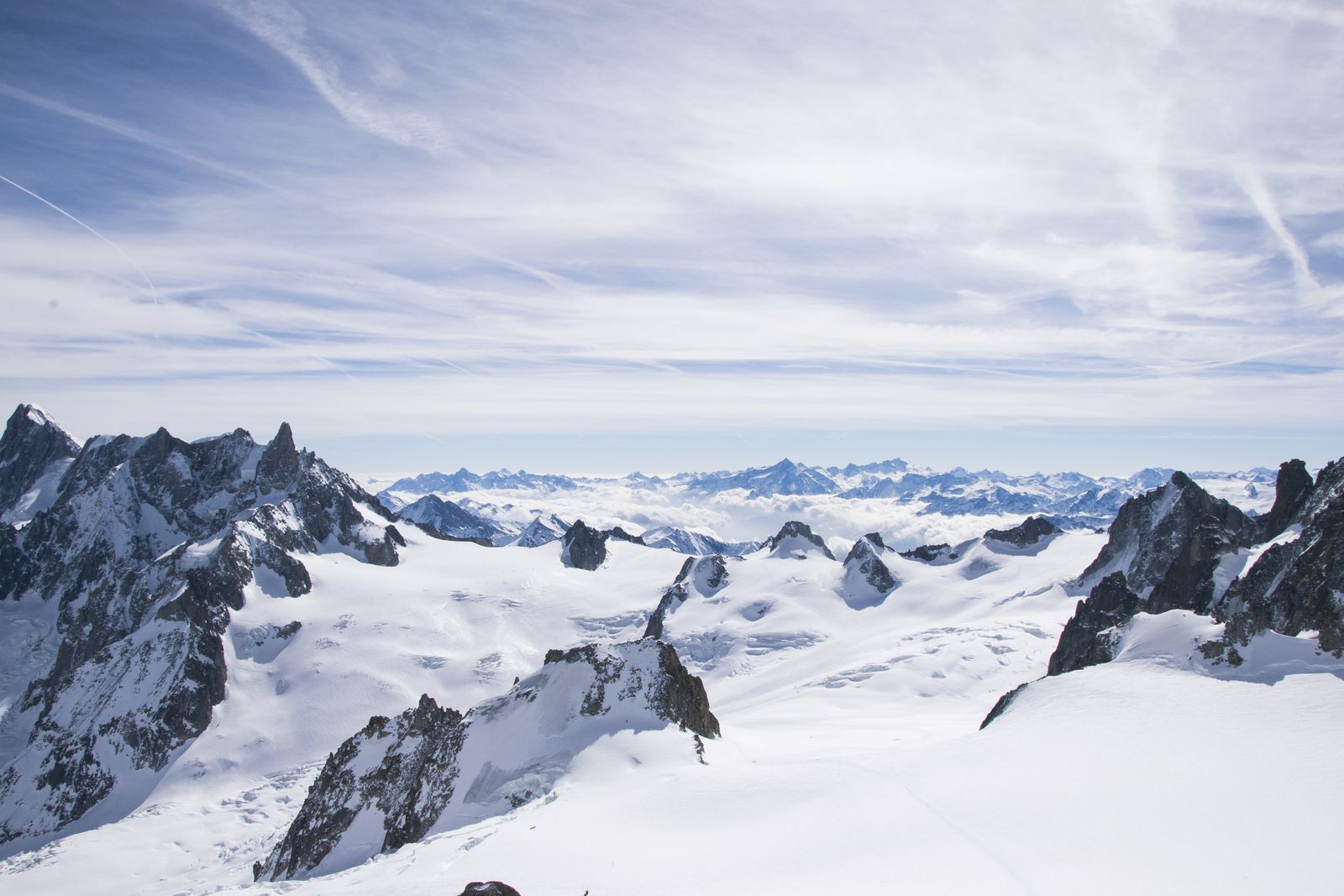 Verschneiter Alpengipfel mit Felsgrat vor blauem Himmel