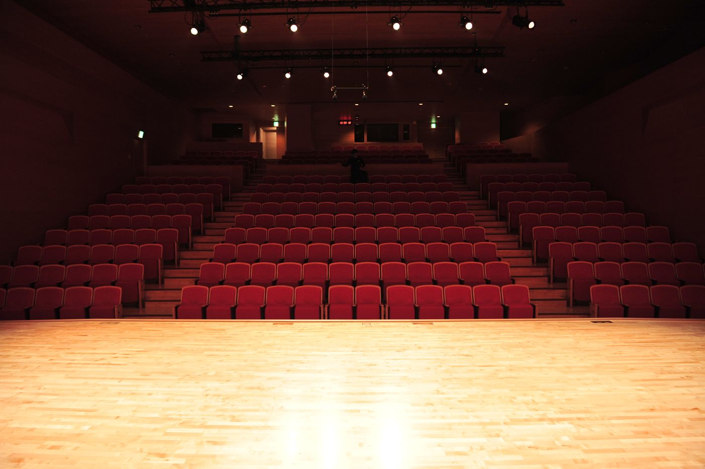 Blick von einer hell beleuchteten Theaterbühne auf leere rote Zuschauerreihen