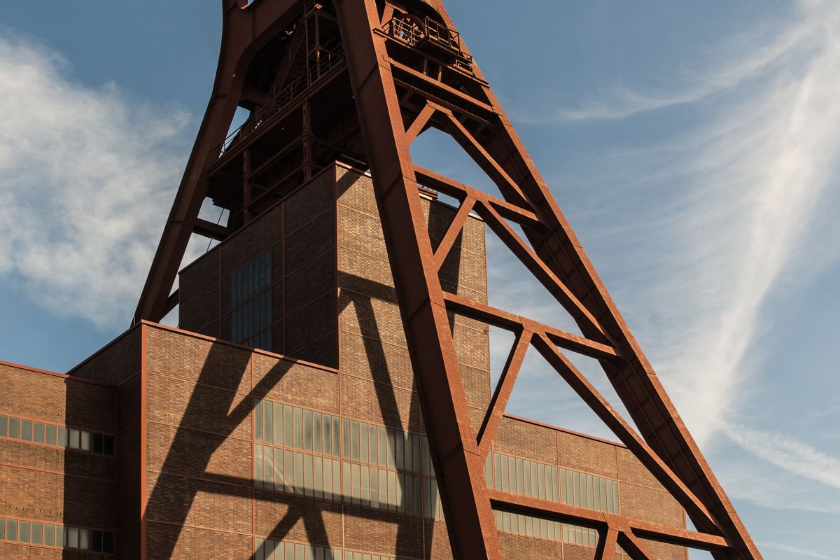 Rostroter Stahlrahmen des Förderturms der Zeche Zollverein in Essen vor blauem Himmel