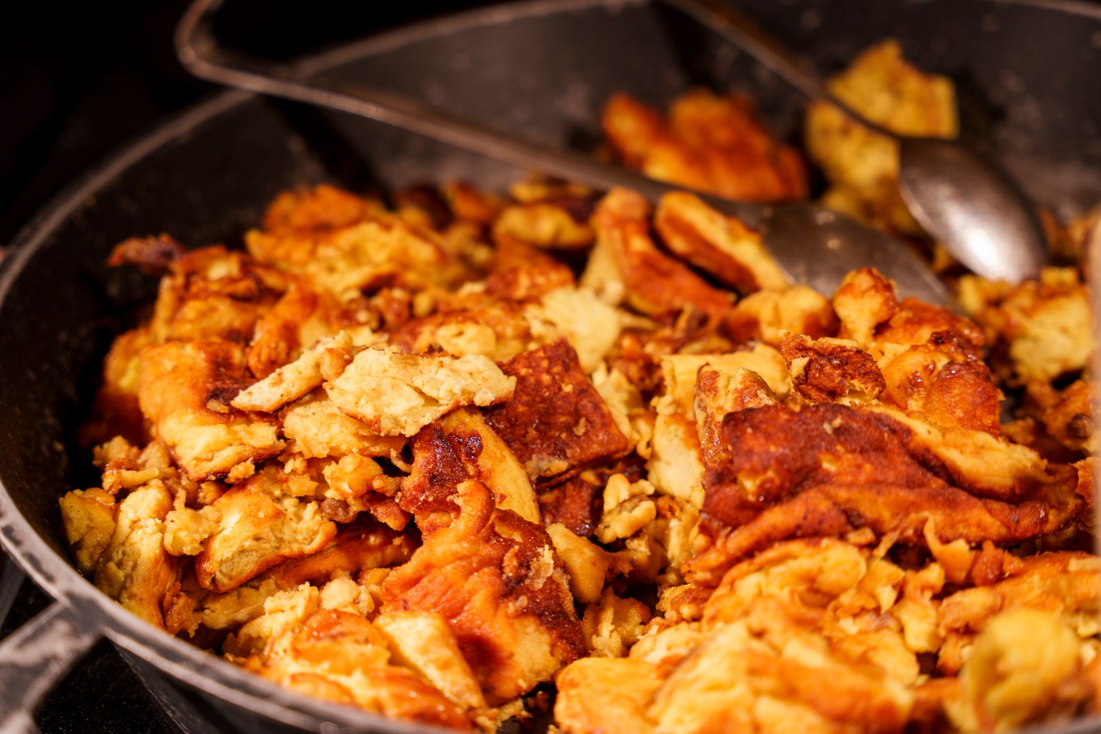 Goldbrauner Kaiserschmarrn in einer gusseisernen Pfanne, servierbereit