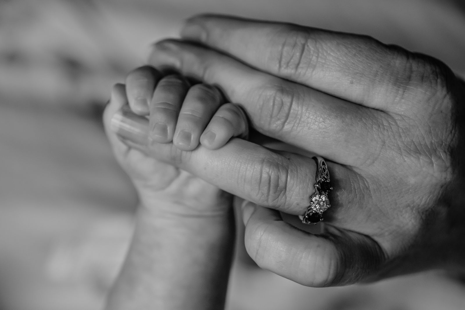 Babyhand umgreift den Finger eines Erwachsenen, Schwarzweißaufnahme
