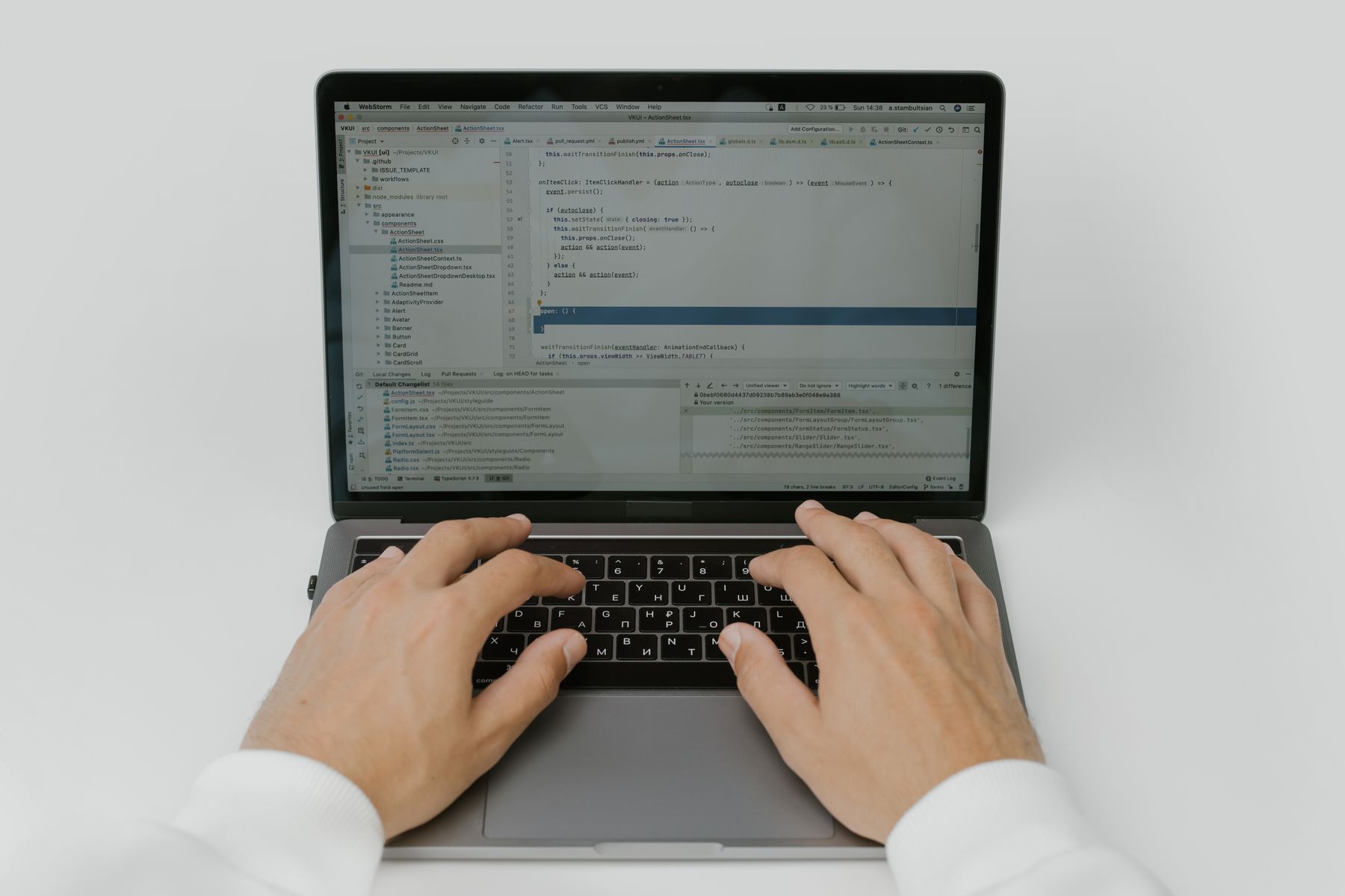 Hände tippen auf einem Laptop, auf dem Bildschirm ist Programmcode zu sehen