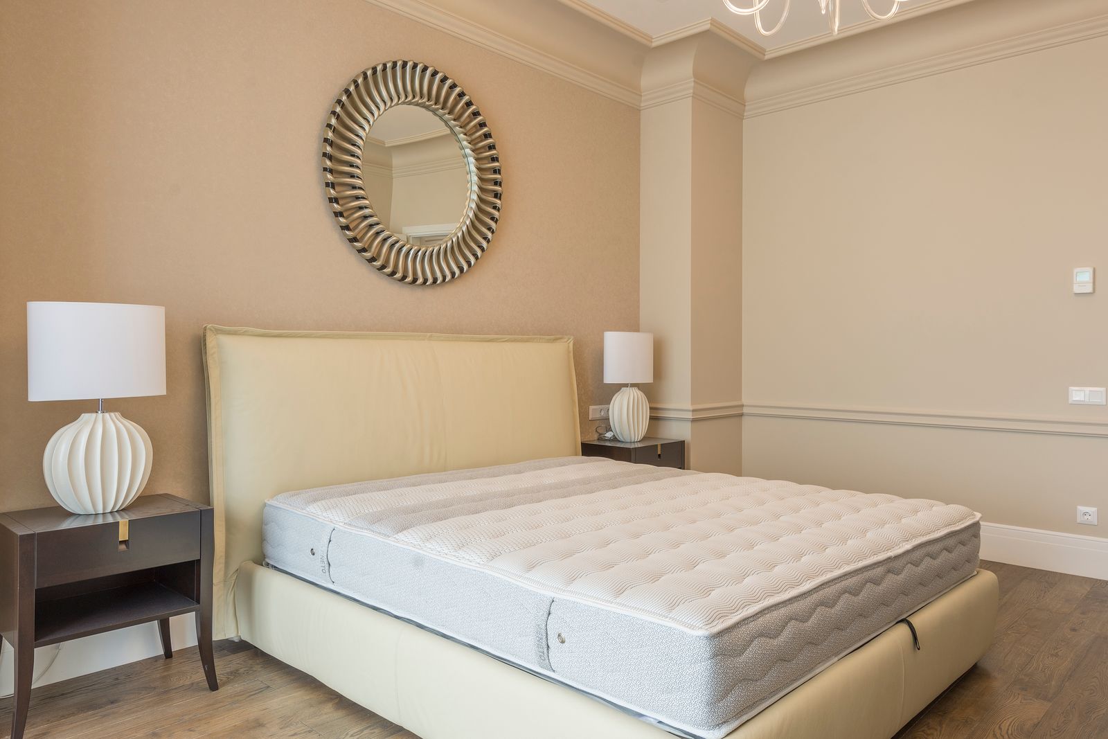 Modernes, helles Schlafzimmer mit weißer Matratze auf einem Bett vor einem Holzschrank