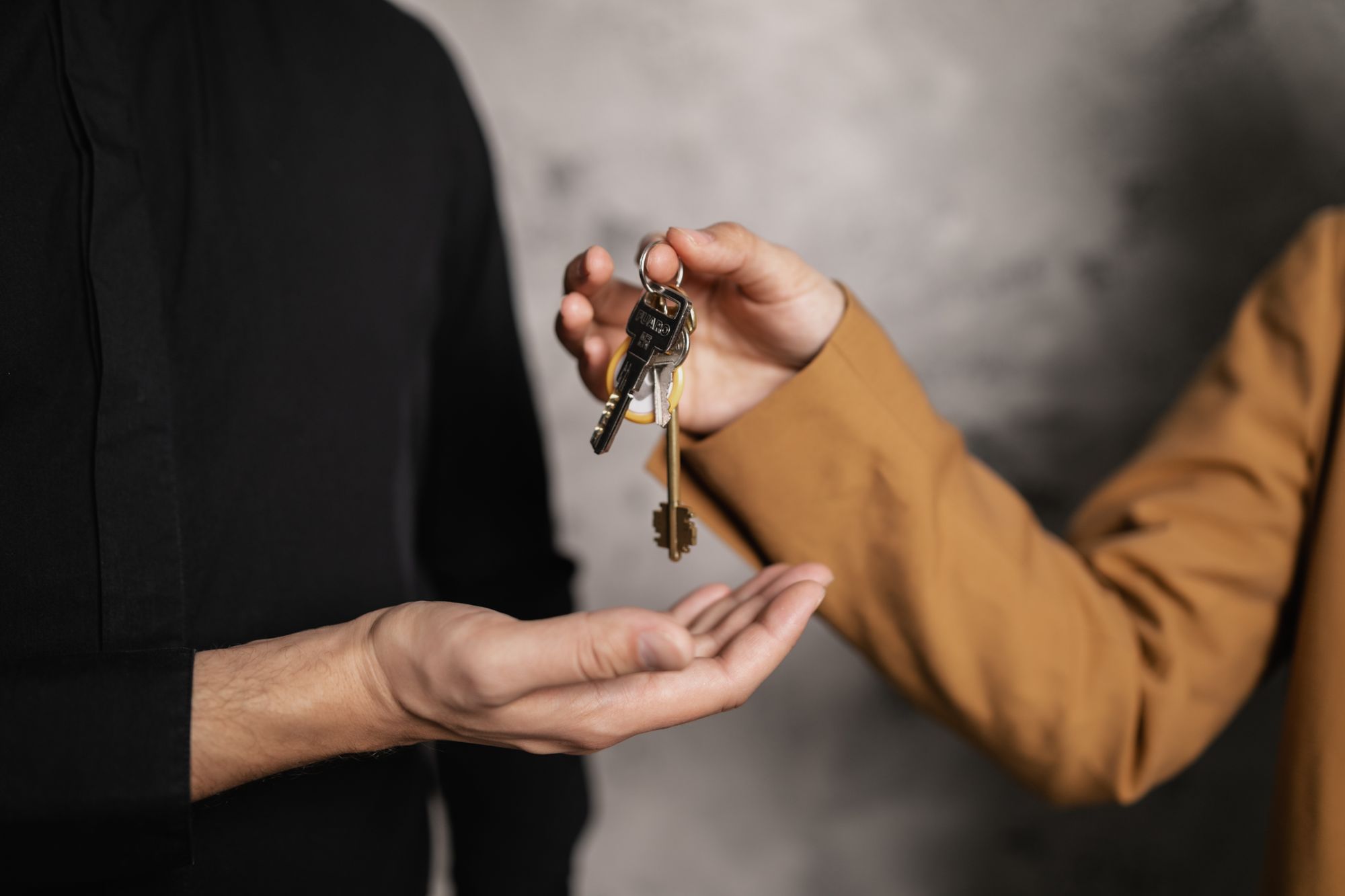 Hand übergibt einen Wohnungsschlüsselbund an eine geöffnete Hand