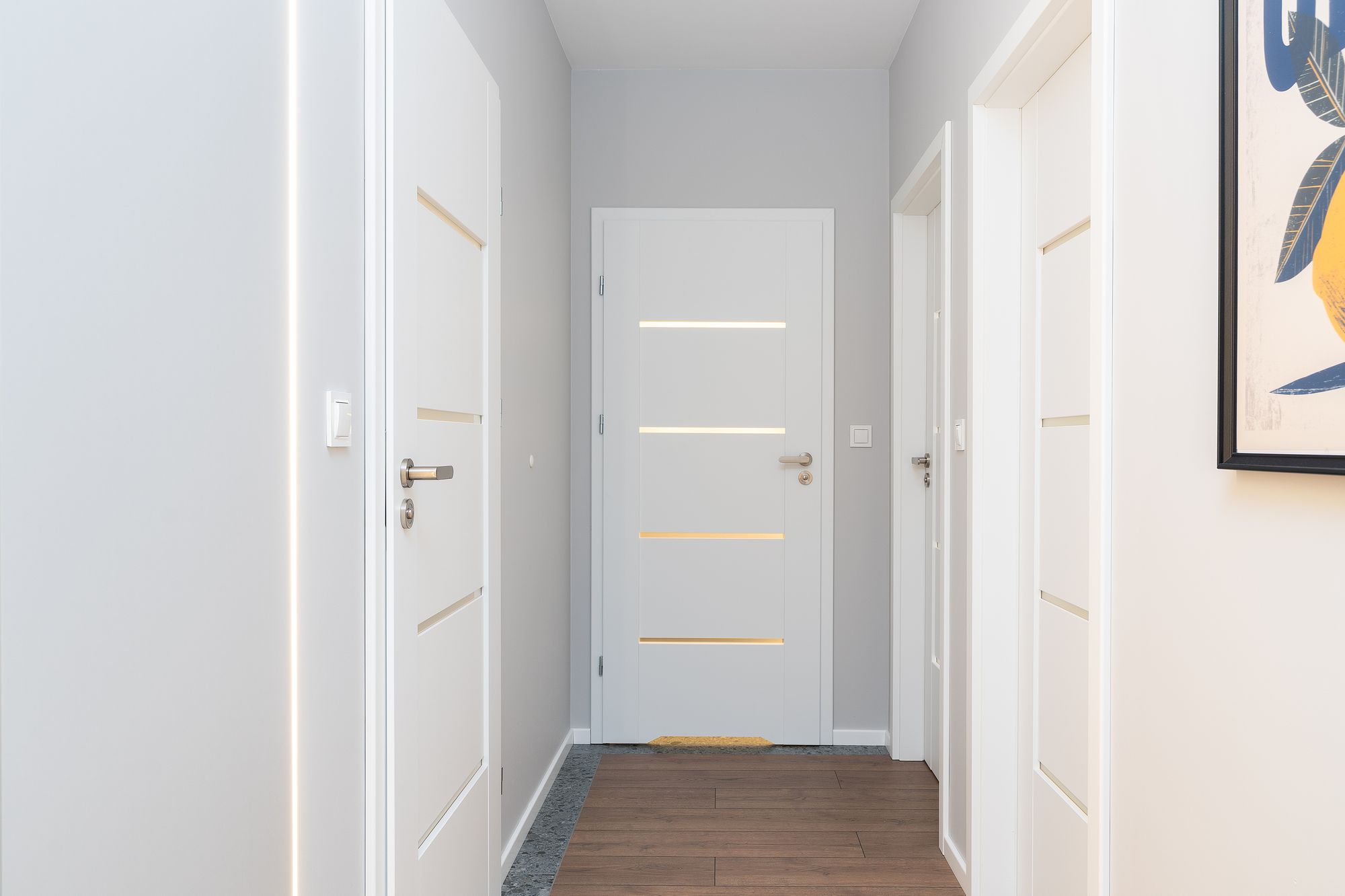 Heller Flur mit weißen Zimmertüren und Holzdielenboden