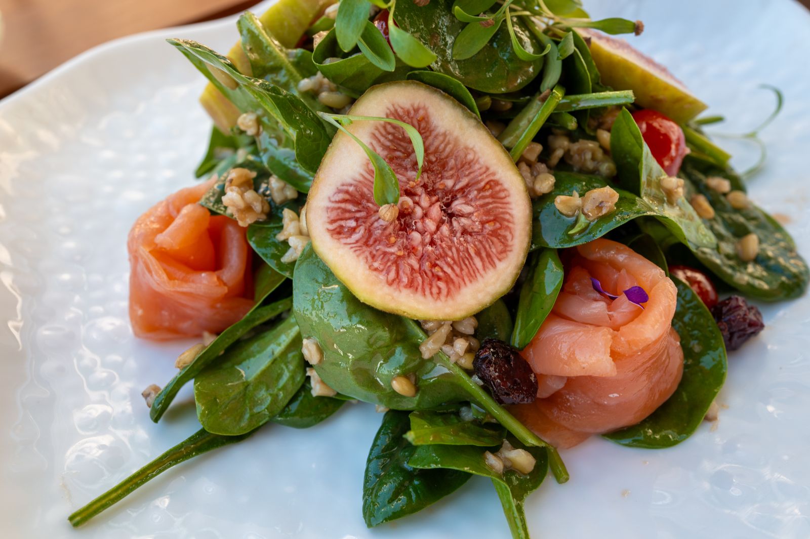 Salat mit geräuchertem Lachs, Feigen und frischem Blattgrün auf einem hellen Teller