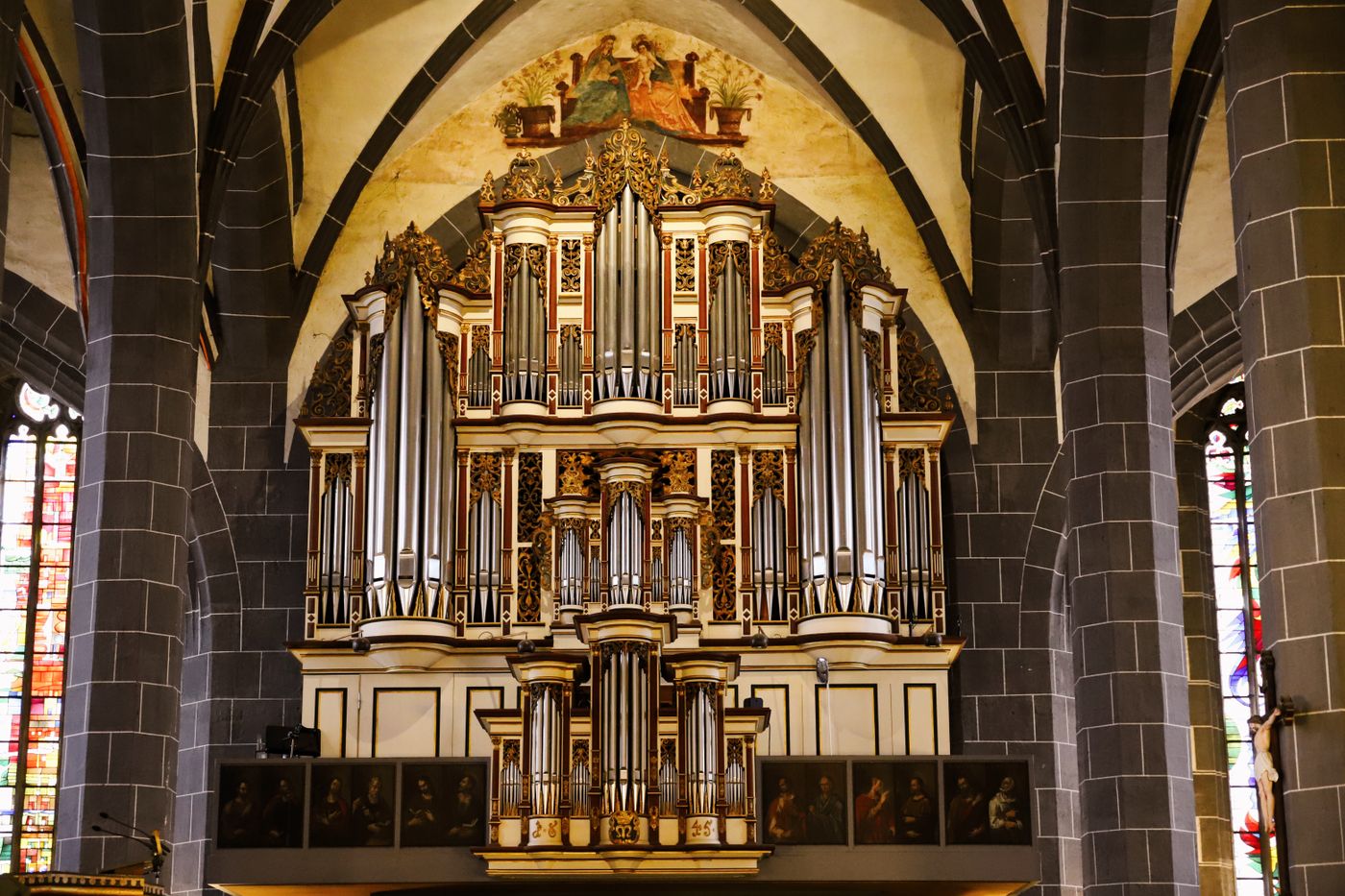 Historische Kirchenorgel mit silbernen Pfeifen und goldenem Schnitzwerk zwischen gotischen Pfeilern