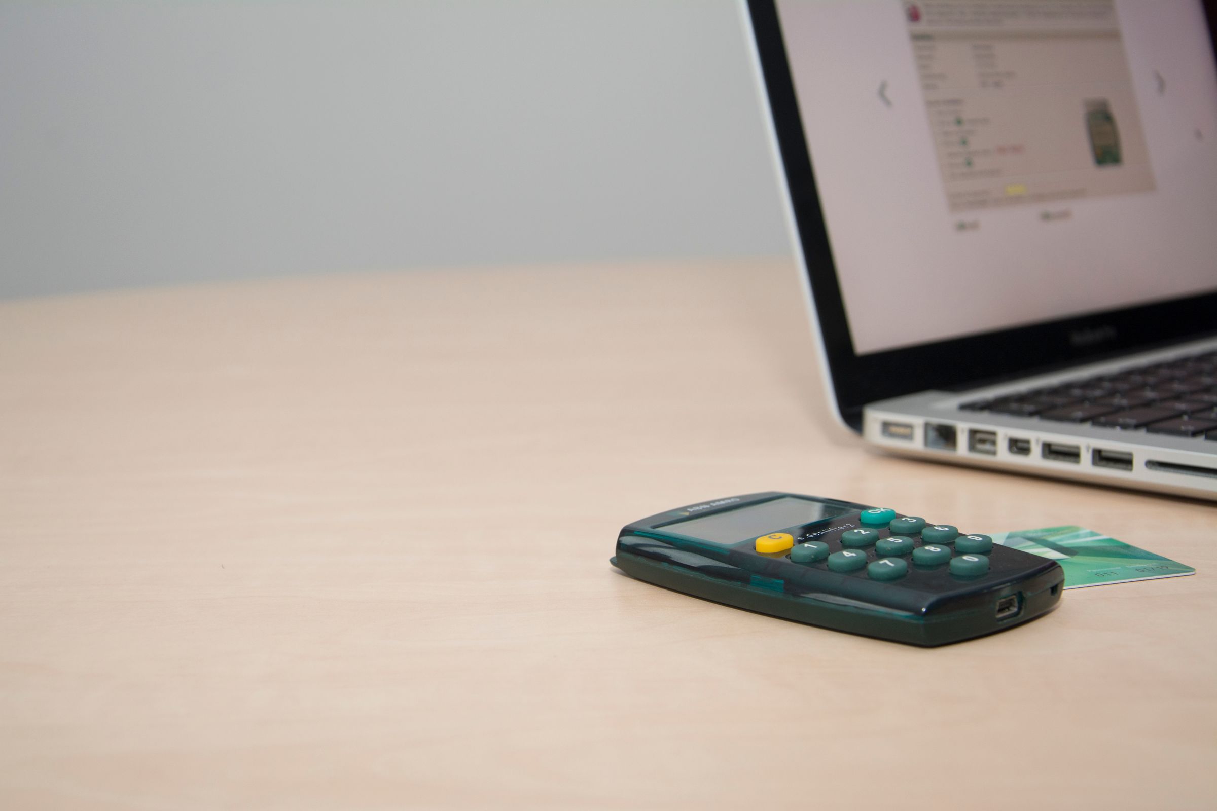 TAN-Generator mit eingesteckter Bankkarte liegt vor einem aufgeklappten Laptop