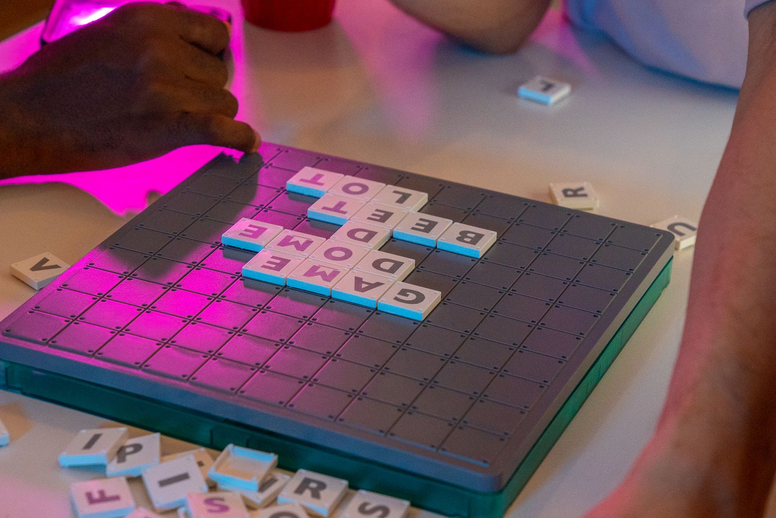 Nahaufnahme zweier Personen beim Brettspiel mit Buchstabenkacheln auf einem Tisch