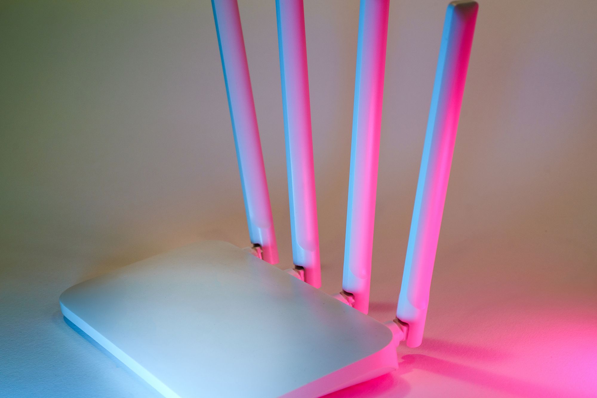 Weißer WLAN-Router mit vier Antennen in blauem und pinkem Neonlicht