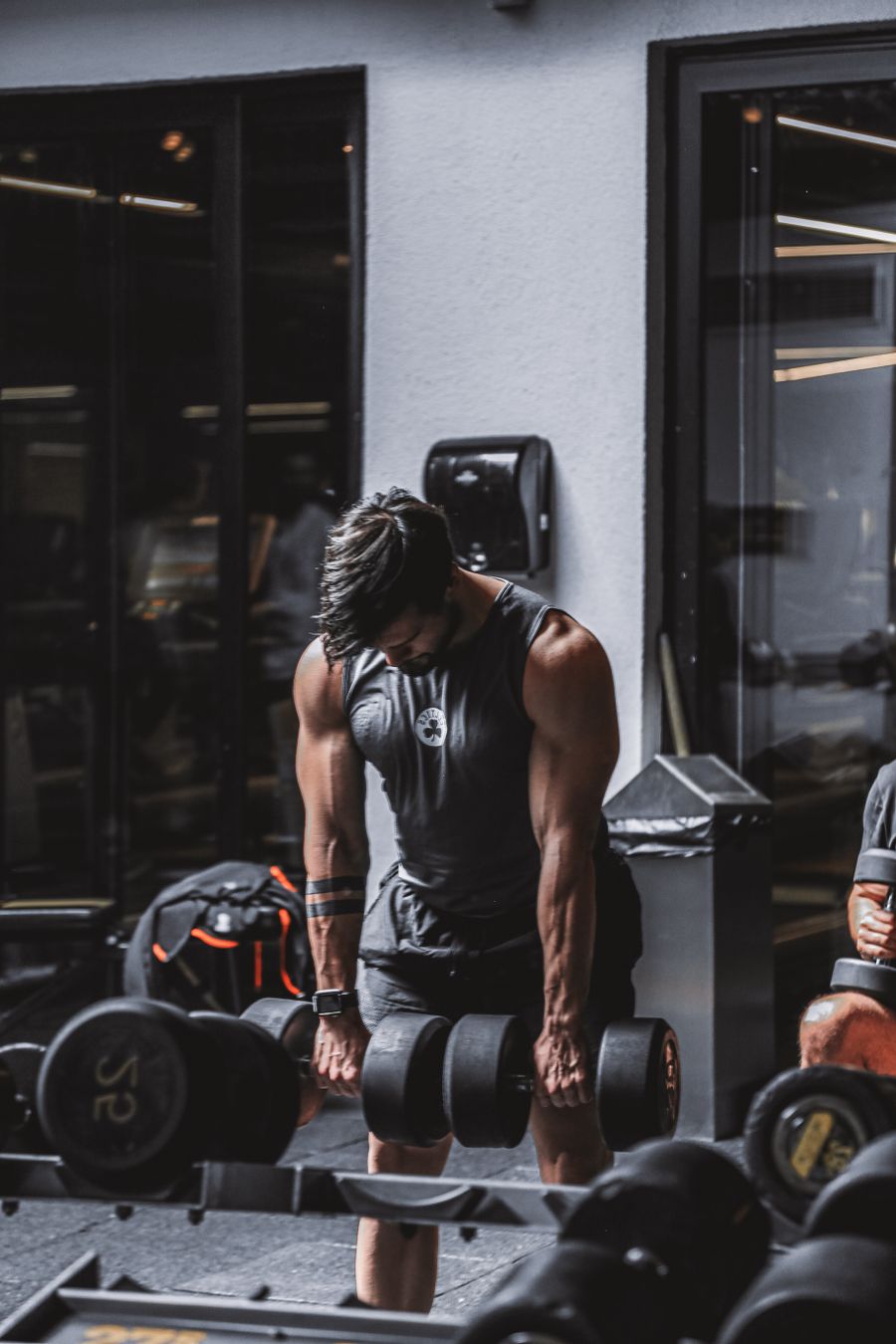 Muskulöser Mann hebt schwere Kurzhanteln im Fitnessstudio beim Krafttraining