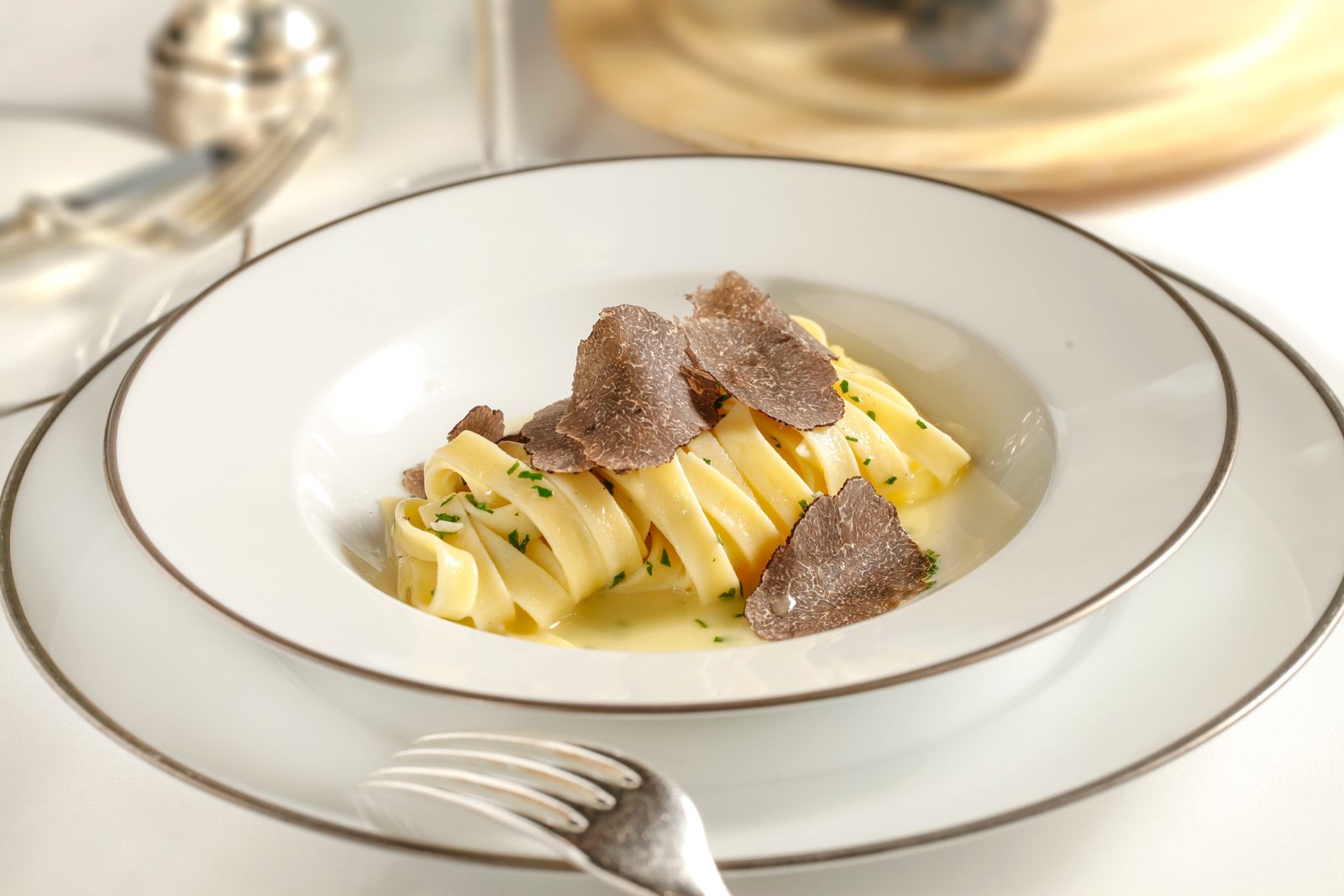 Pasta mit feinen schwarzen Trüffelscheiben auf weißem Teller