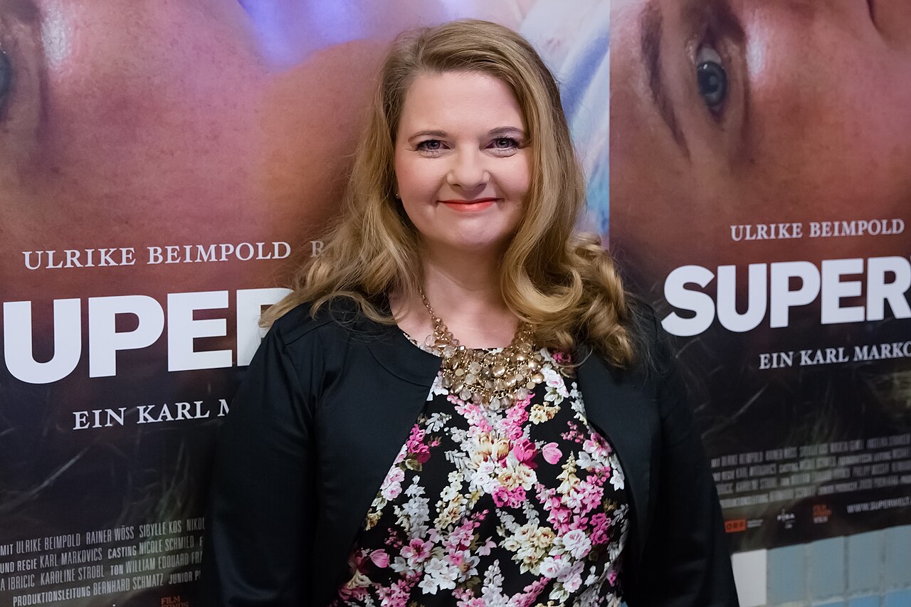Ulrike Beimpold lächelt vor Plakaten zum Film Superwelt bei der Wien-Premiere im Gartenbaukino