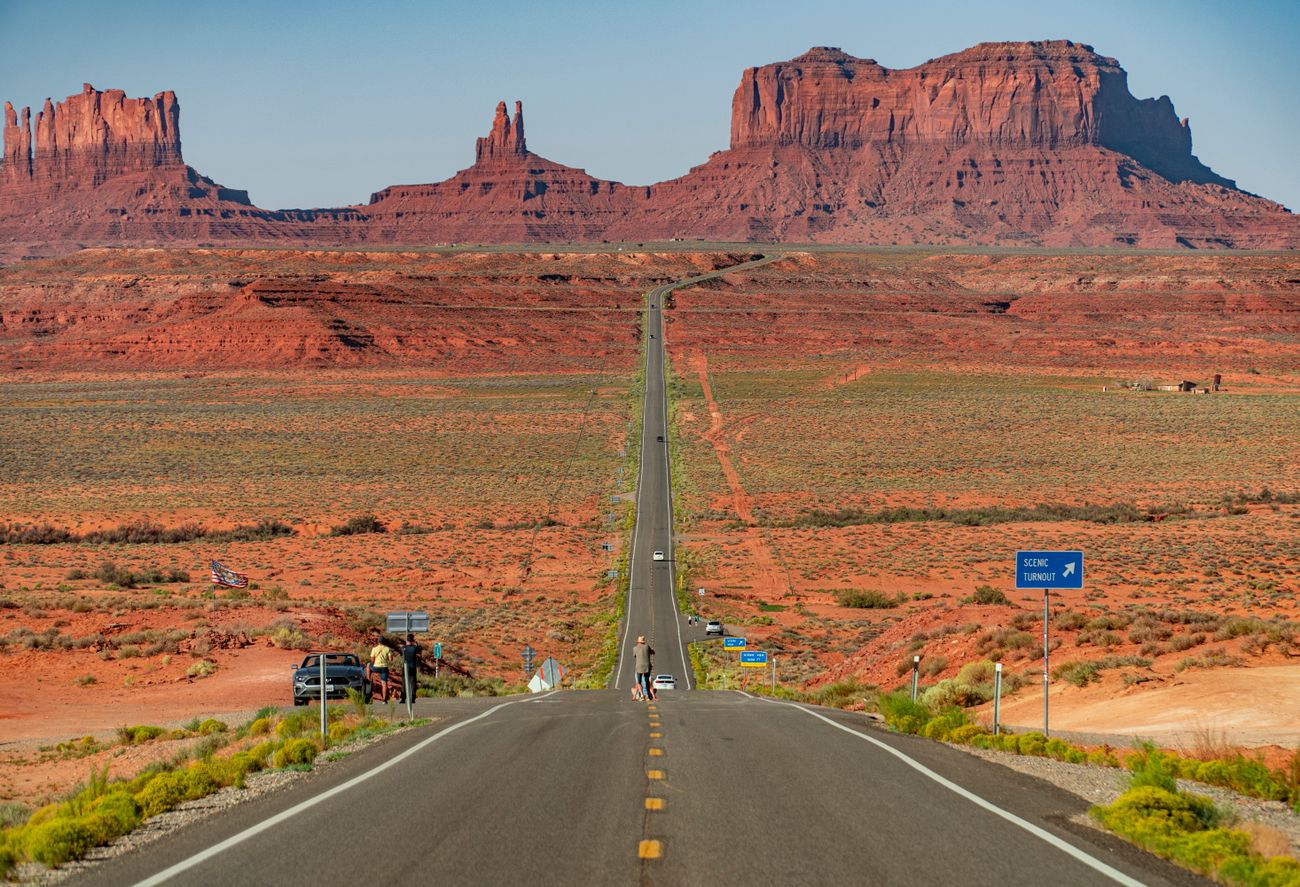 Gerade Straße durch rote Wüstenlandschaft auf die Tafelberge des Monument Valley zu