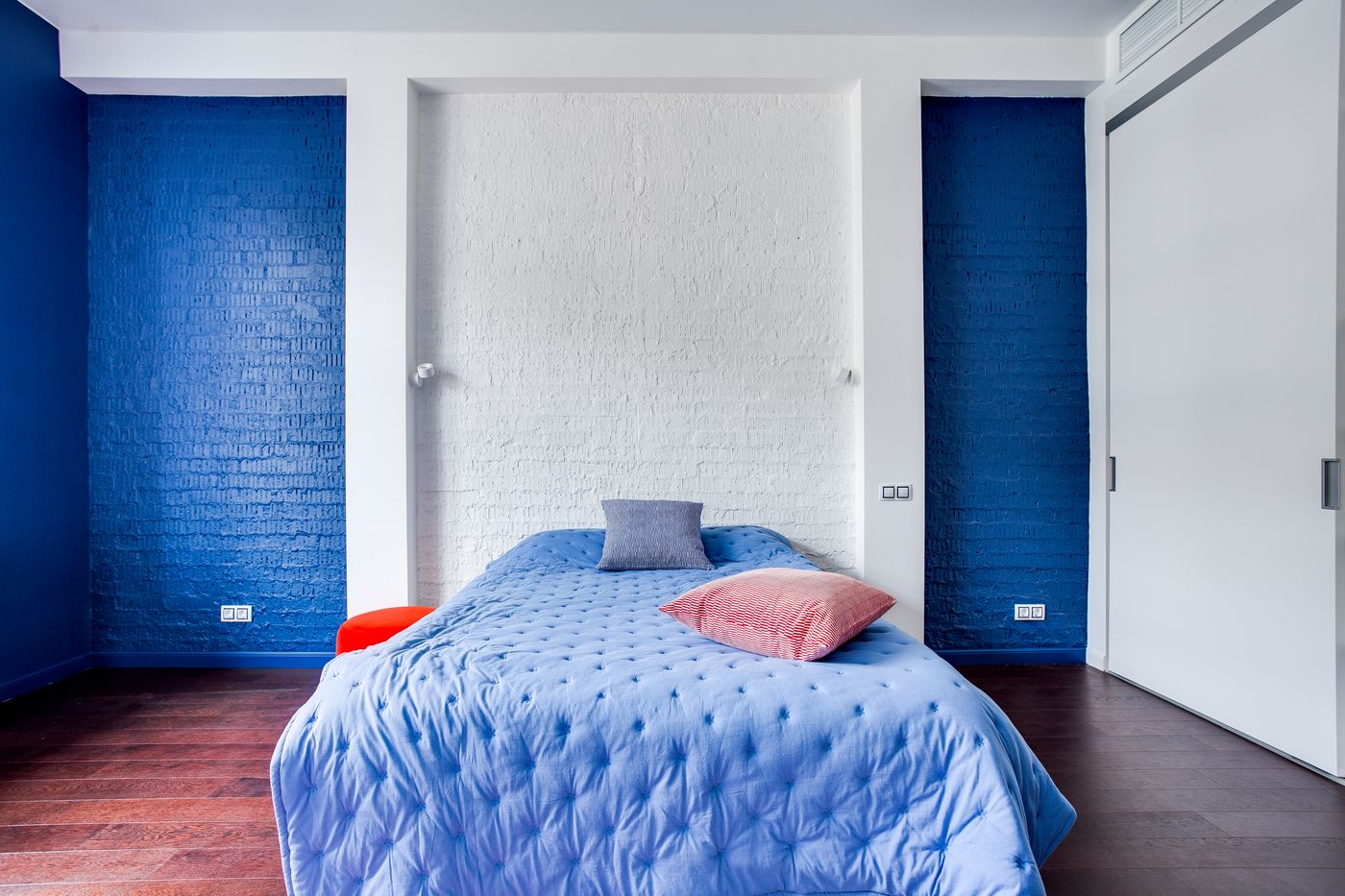 Modernes Schlafzimmer mit dunkelblauer Akzentwand und gemütlichen Kissen auf weißem Bett