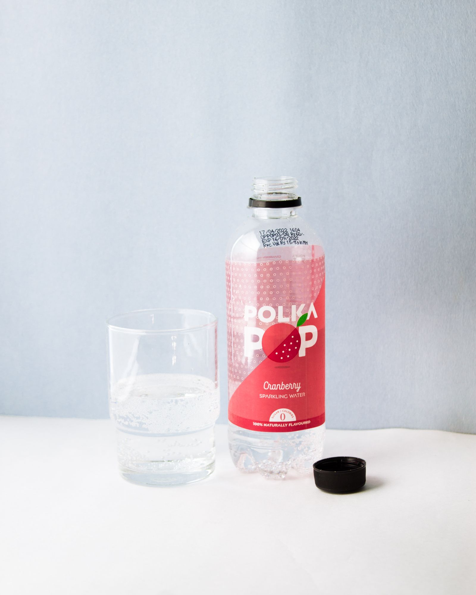 Glas mit Sprudelwasser neben einer Flasche kohlensäurehaltiges Wasser auf hellem Untergrund