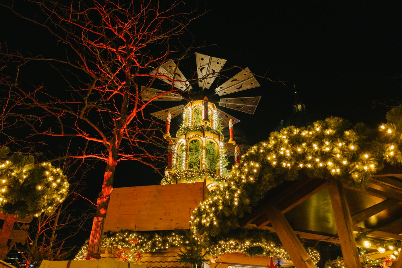 Beleuchtete Weihnachtsmarktbuden mit Lichterketten bei Nacht