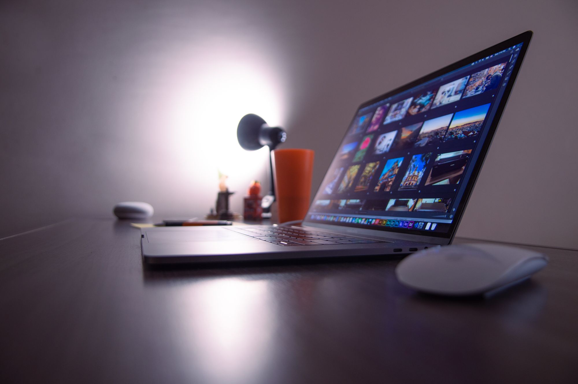 Aufgeräumter Schreibtisch mit aufgeklapptem Laptop, Schreibtischlampe und Zubehör
