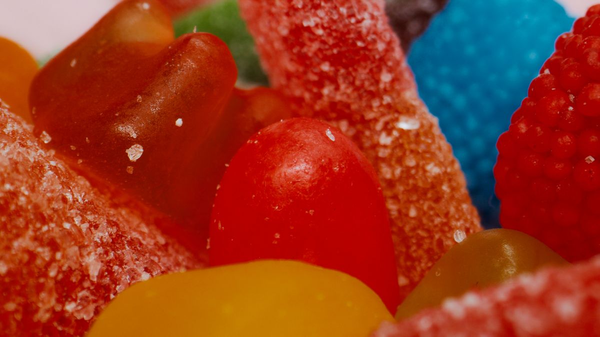Nahaufnahme bunter Fruchtgummis, teils mit Zuckerkruste, in Rot, Gelb, Blau und Grün